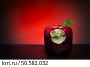 Red, bitten, cube apple on a red background and black floor. Стоковое фото, агентство Ingram Publishing / Фотобанк Лори