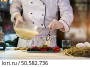 Spoon puts cream into glass. Hand of cook holding bowl. Mixture of eggs and milk. Italian pastry chef.. Spoon puts cream into glass. Стоковое фото, агентство Ingram Publishing / Фотобанк Лори