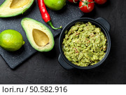 Bowl of guacamole with fresh ingredients on a black table. Стоковое фото, агентство Ingram Publishing / Фотобанк Лори