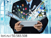 A businessman accesing internet and information technology via tablet / gadget in his hand. Стоковое фото, агентство Ingram Publishing / Фотобанк Лори