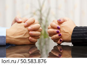 Man and woman sits at a desk with hands clasped. marital problems, conflicts and stubborn concept. Стоковое фото, агентство Ingram Publishing / Фотобанк Лори