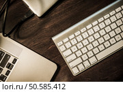 Entrepreneur Work Desk. Modern Working Desk. Laptop Computer, Wireless Keyboard and Portable External Drive. Dark Wooden Desk Top View. Стоковое фото, агентство Ingram Publishing / Фотобанк Лори