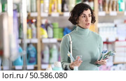 Positive middle-aged female customer choosing convenient toothbrush in large retail store. Стоковое видео, видеограф Яков Филимонов / Фотобанк Лори