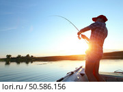 Young man fishing on a lake from the boat at sunset. Стоковое фото, агентство Ingram Publishing / Фотобанк Лори