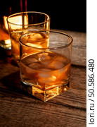 Whiskey, bourbon or brown rum with ice on wood table. Whiskey or bourbon. Стоковое фото, агентство Ingram Publishing / Фотобанк Лори