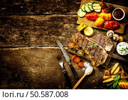 Preparing t-bone steak and roast vegetables in a country kitchen with bell peppers, mushrooms, tomato, potato, mangetout peas, and corn on a rustic wooden table with copyspace. Preparing t-bone steak and roast vegetables. Стоковое фото, агентство Ingram Publishing / Фотобанк Лори