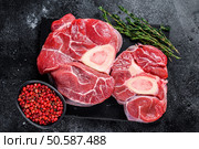 Raw beef meat osso buco shank steak,  italian ossobuco. Black background. Top view. Стоковое фото, агентство Ingram Publishing / Фотобанк Лори