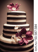 Details of a wedding or a birthday cake, triple size, in studio on white background. Purple sugar flowers as main decoration. . Стоковое фото, агентство Ingram Publishing / Фотобанк Лори