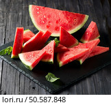 Watermelon slices and half decorated with mint on a black slate board. Стоковое фото, агентство Ingram Publishing / Фотобанк Лори