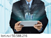 A businessman accesing internet and information technology via tablet / gadget in his hand. Стоковое фото, агентство Ingram Publishing / Фотобанк Лори