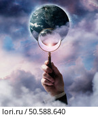 Businessman holding magnifying glass up to planet Earth. 24316772. Стоковое фото, агентство Ingram Publishing / Фотобанк Лори