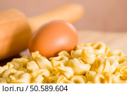 Closeup tortellinis piled up next to an egg and blurry rolling pin background.. Closeup tortellinis piled up next to an egg and blurry rolling pin background. Стоковое фото, агентство Ingram Publishing / Фотобанк Лори