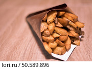 Potatoes wedges in paper cone on a wooden table. Стоковое фото, агентство Ingram Publishing / Фотобанк Лори