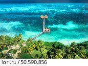 Aerial view of bungalow, jetty, white sandy beach, ocean on summer sunny day. Restaurant on the sea. Top drone view of wooden hotel, azure water, pool, green palms. Luxury resort in Zanzibar. Tropical. Стоковое фото, агентство Ingram Publishing / Фотобанк Лори
