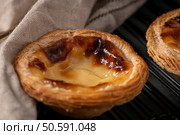 Golden-brown pastries with flaky, layered crusts and caramelized tops rest on a cooling rack, partially covered by a beige cloth, showcasing their delicious texture. Стоковое фото, агентство Ingram Publishing / Фотобанк Лори