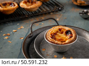 Golden-brown Portuguese custard tart on a rustic metal tray with a wire rack in the background. Стоковое фото, агентство Ingram Publishing / Фотобанк Лори