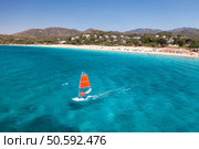 Aerial view of windsurfer on blue sea at sunny summer day. Windsurfing. Extreme sport and vacation. Top view of man on windsurfer board, waves, clear azure water in Sardinia, Italy. Tropical landscape. Стоковое фото, агентство Ingram Publishing / Фотобанк Лори