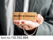 Self improvement, message on the white paper / business concept. Close,Up,Conceptual,Businessman,Showing,Wooden,Blocks,With,Believe,In. Стоковое фото, агентство Ingram Publishing / Фотобанк Лори