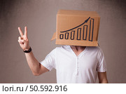 Young man standing and gesturing with a cardboard box on his head with diagram. Стоковое фото, агентство Ingram Publishing / Фотобанк Лори