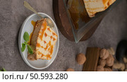 A delectable slice of molotov pudding, generously drizzled with caramel and garnished with fresh mint, presented on a small, elegant plate with a spoon. Стоковое фото, агентство Ingram Publishing / Фотобанк Лори