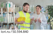 Male builder chooses pills for headaches and joint pain, and a female pharmacist recommends a cooling ointment for back pain. Builder buys medicines at a pharmacy. Стоковое видео, видеограф Яков Филимонов / Фотобанк Лори
