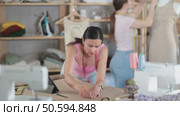 Woman tailor draws dress diagram scheme on paper. Companion worker in background with mannequin. Стоковое видео, видеограф Яков Филимонов / Фотобанк Лори