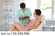 Middle-aged woman patient lying on clinical chair discussing face aesthetic procedures with doctor. Стоковое видео, видеограф Яков Филимонов / Фотобанк Лори