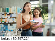 Woman with teen girl are busy choosing ointment for bruises at pharmacy. Стоковое фото, фотограф Яков Филимонов / Фотобанк Лори