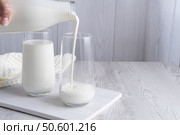 Pouring homemade kefir, buttermilk or yogurt with probiotics. Yogurt flowing from glass bottle on light background. Стоковое фото, фотограф Наталия Попова / Фотобанк Лори