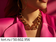Fashion model wearing gold chain and big earrings posing in pink dress. Стоковое AI-изображение, AI-художник Иван Рябоконь / Фотобанк Лори
