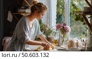 Woman preparing fresh pastry with ingredients on counter in a bright kitchen during daytime. Стоковое AI-изображение, AI-художник Сергей Толмачёв / Фотобанк Лори