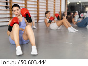 Girls in boxing gloves are sitting on floor, doing abdominal exercise and working with hands. Стоковое фото, фотограф Яков Филимонов / Фотобанк Лори