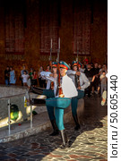 12.08.2024. Russia. Volgograd. Mamayev Kurgan.Three uniformed guards perform a synchronized military march with rifles, surrounded by a crowd of onlookers at a ceremonial event with sunlight casting shadows on the stone floor. Редакционное фото, фотограф Алина Лебедь / Фотобанк Лори