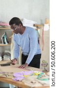 African man tailor draws dress diagram scheme on paper, laptop on table. Стоковое видео, видеограф Яков Филимонов / Фотобанк Лори