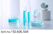Laboratory glassware with blue liquid in serene setting showcasing scientific experimentation and observation. Стоковое AI-изображение, AI-художник Сергей Толмачёв / Фотобанк Лори