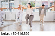 Young girl standing performs basic hip hop movements in front of group of students. Стоковое фото, фотограф Яков Филимонов / Фотобанк Лори
