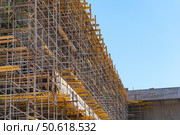 Фасад здания с установленными строительными лесами. Building under construction in scaffolding around the house for cement plastering work on the high outer wall. Стоковое фото, фотограф Татьяна Д / Фотобанк Лори