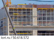 Фасад здания с установленными строительными лесами. Building under construction in scaffolding around the house for cement plastering work on the high outer wall. Стоковое фото, фотограф Татьяна Д / Фотобанк Лори