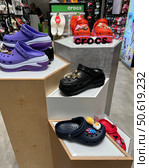 Belgrade, Serbia. August 03, 2024. A colorful display of Crocs-style shoes lines a store wall. The children shoes come in a variety of bright colors and styles. Редакционное фото, фотограф Ирина Старикова / Фотобанк Лори
