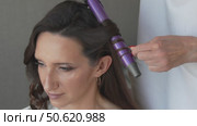 Hairdo curling woman hairstylist, before party indoor, stylist curls dark hair with curling iron, for the event. Стоковое видео, видеограф svetograph / Фотобанк Лори
