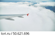 Airplane wing gliding above fluffy clouds, revealing expansive landscape stretching beneath. Стоковое фото, фотограф Mikhail Davidovich / Фотобанк Лори