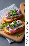 Delicious sprats sandwiches with red onion and herbs on wooden board. Стоковое AI-изображение, AI-художник Юрий Поздников / Фотобанк Лори
