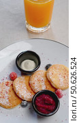 Authentic Slavic syrniki pancakes nestled on gray tablecloth, accompanied by vibrant red berries, creamy sour cream, and fresh orange juice. Стоковое видео, видеограф Данил Руденко / Фотобанк Лори