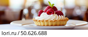 Appetizing raspberry tart and mint. Raspberry danish cake on plate on table and coffee. Tartlets raspberry fruit with vanilla custard, whipped cream served in a cafe. Blurred bokeh interior background. Стоковое AI-изображение, AI-художник Марина Демидюк / Фотобанк Лори