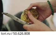 Slow-motion video of women's hands peeling large, soil-covered potatoes with an old metal knife in a village cooking setting. Стоковое видео, видеограф Татьяна Степанищева / Фотобанк Лори