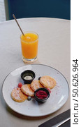 Fluffy homemade pancakes topped with mixed berries, dollop of cream, drizzled jam, positioned beside orange juice on neutral ceramic plate. Стоковое видео, видеограф Данил Руденко / Фотобанк Лори