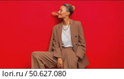 Fashion model showcases stylish brown outfit against bright red backdrop in urban setting. Стоковое AI-видео, аниматор Сергей Толмачёв / Фотобанк Лори