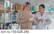 Smiling friendly young female pharmacist recommending suitable prenatal vitamins and supplements to pregnant customer, explaining use and dosage. Стоковое видео, видеограф Яков Филимонов / Фотобанк Лори