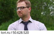 Confident Businessman in Natural Setting. Man stands in front of lush green backdrop. Remote working. Portrait of happy mid adult male wearing formal clothes, shirt and tie, glasses. Find inspiration. Стоковое видео, видеограф Марина Демидюк / Фотобанк Лори