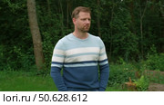 Handsome young man standing outdoors. Male thinking looking around feel happy, calm and serious. Green park background. Guy business employer, businessman manager inspired in nature. Diversity People. Стоковое видео, видеограф Марина Демидюк / Фотобанк Лори